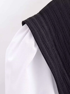 Close-up of contrast patchwork shirt with black pleated texture and white plain fabric