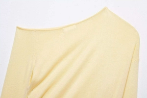Detailed close-up of the elegant boat neck and fine stitching on the yellow knit sweater