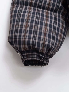 Close-up of elastic cuff and silver metal button on vintage plaid quilted jacket
