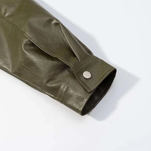 Close-up of olive green leather jacket cuff with a silver metal snap button detail