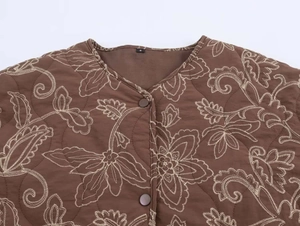 Detail shot of brown quilted jacket featuring beige floral embroidery and round buttons