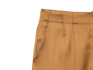 Detail of high waist satin trousers in dark brown showing smooth fabric and pocket stitching