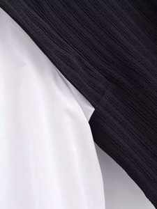 Detailed macro view of the black pleated fabric and smooth white cotton material texture