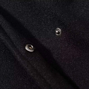 Macro detail of black wool coat fabric with high-quality silver metal snap buttons