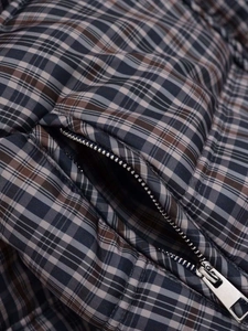 Detail of vintage plaid quilted jacket showing metal zipper pocket and woven texture