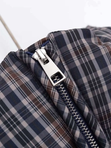 Detailed close-up of a silver metal zipper on vintage plaid quilted cotton fabric material