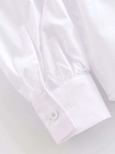 Detailed close-up of white shirt sleeve cuffs with single button and fine pleated seams