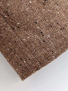 Macro shot of brown herringbone tweed fabric with detailed multi-colored fiber texture