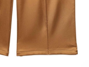 Macro detail of bronze satin trousers showing smooth fabric texture and precise hemline