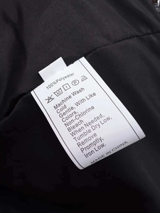 Detail of white laundry care label on black quilted polyester fabric with wash icons