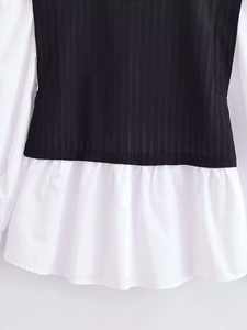 Detail view of the black textured knit fabric stitched with white ruffled shirt hemline