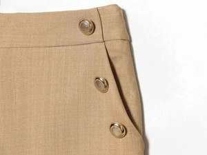 Detailed close-up of textured gold buttons on khaki high-waist wide-leg trousers
