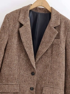 Detail of brown herringbone tweed blazer showing lapels, buttons and pocket flap