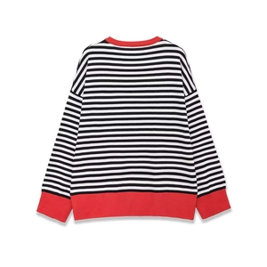 Détail du col et des poignets rouges côtelés sur un pull en maille rayé noir et blanc