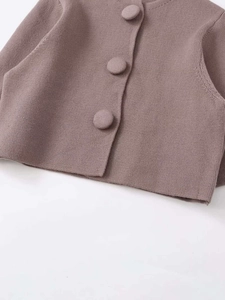 Detail der Strickjacke mit eleganten stoffbezogenen Knöpfen und feiner Strickstruktur