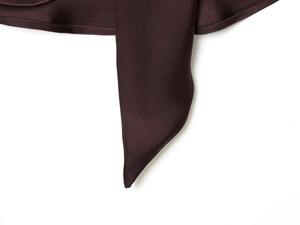 Detail of a deep chocolate satin dress showing the smooth fabric texture and hem stitching