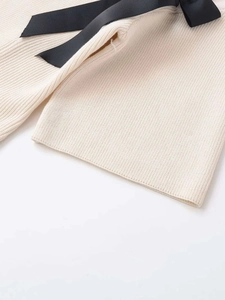 Detailed macro view of cream rib knit fabric texture with a black ribbon bow detail
