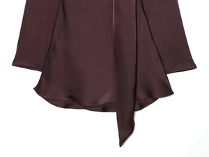 Detailed view of the dark brown satin dress showing curved hem, sleeves, and soft draping silk texture