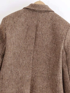 Detail shot showing the back of a brown herringbone tweed blazer with quality stitching