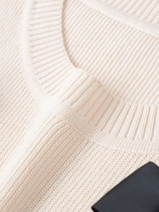 Macro shot of the ribbed knit crew neck and fine stitching on this cream sweater
