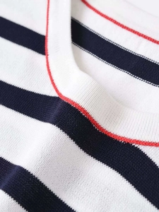 Close-up of knit sweater featuring navy stripes and a vibrant red trim neckline