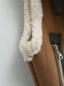 Detail of brown faux suede vest showing white sherpa lining and silver metal zipper