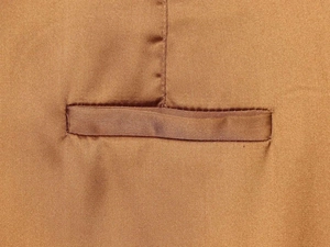 Detailed view of the smooth satin fabric and welt pocket stitching on high waist trousers