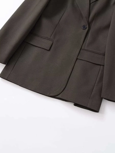 Detailed view of dark olive green single-breasted blazer with textured weave and flap pockets