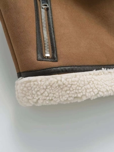 Close-up of contrast brown suede vest with thick white faux shearling lining and leather trim