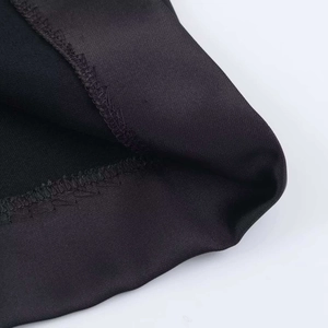 Gros plan du tissu noir montrant la texture sergée et les détails de couture surjet