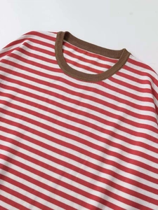Détail d'un pull en maille rayé rouge et blanc avec un col rond côtelé marron