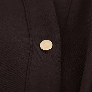 Macro detail of high-quality fabric texture and a polished golden button on a midi shirt dress