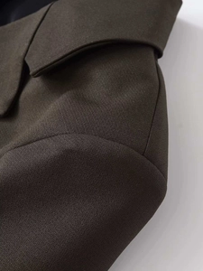 Close-up detail of dark brown single-breasted blazer with premium textured woven fabric