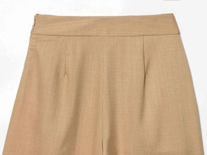 Detail of high waist trousers showing side invisible zipper and pleat design
