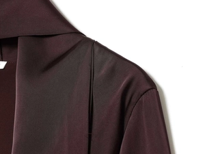 Detailed view of the elegant satin fabric texture and stitching on the burgundy high neck dress