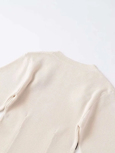 Detailed close-up of ribbed crew neck and high-density knit stitching on off-white sweater