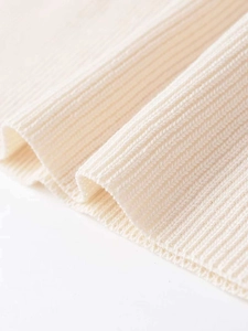 Detailed macro shot of beige ribbed knit texture showing soft thick fabric quality