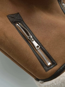Detailed close-up of brown suede vest with white faux shearling lining and silver metal zipper