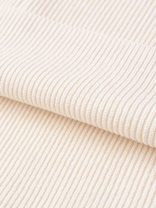 Macro shot of off-white ribbed knit fabric texture showing high-quality vertical weave