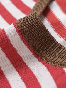 Détail macro du tricot à rayures rouges et blanches avec col contrasté en maille côtelée brune