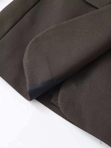 Detail of dark brown blazer featuring rounded hem and contrast navy blue lining