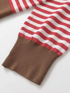 Détail rapproché des poignets en tricot à rayures rouges avec bords côtes marron
