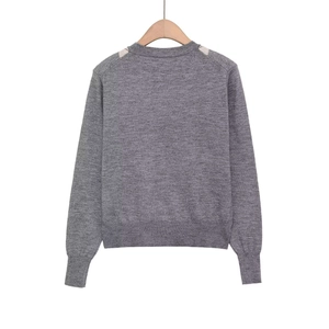 Grey knit sweater with beige diamond pattern and ribbed cuffs shown on a wooden hanger