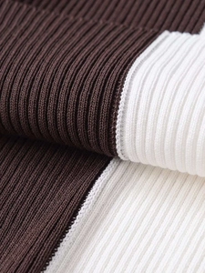 Detailed close-up of ribbed knit fabric texture with dark brown and cream color stitching