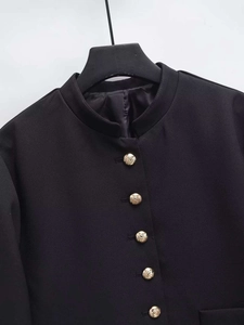 Detailed close-up of vintage gold crest metal buttons on a black stand collar jacket