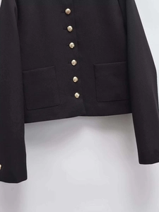 Detail of black vintage jacket featuring golden embossed buttons and symmetrical pockets
