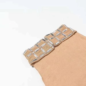 Détail du tissu en maille chair avec embellissements en strass rectangulaires sur le col