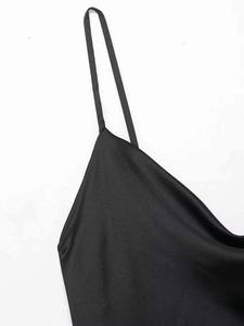 Detail of black satin dress featuring thin spaghetti straps and elegant draped neckline