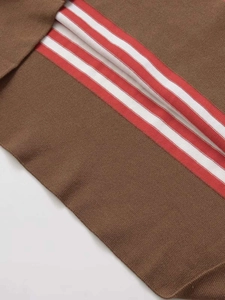 Gros plan sur la maille fine du pull marron avec rayures horizontales rouges et blanches
