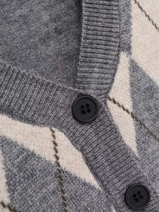 Close-up of grey argyle knit cardigan featuring black buttons and soft fabric texture